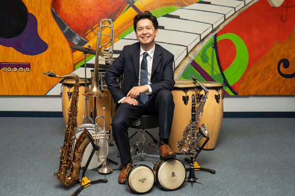 MKE Latin Legends band leader posing with his instruments wearing suit