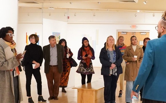 Audience standing in the gallery with coffee and churros at Latino ARts in Milwaukee WI